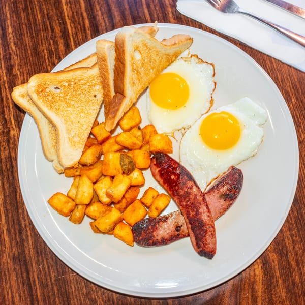 A J's Brothers breakfast plate with fried eggs, sausage, home fries, and toast.
